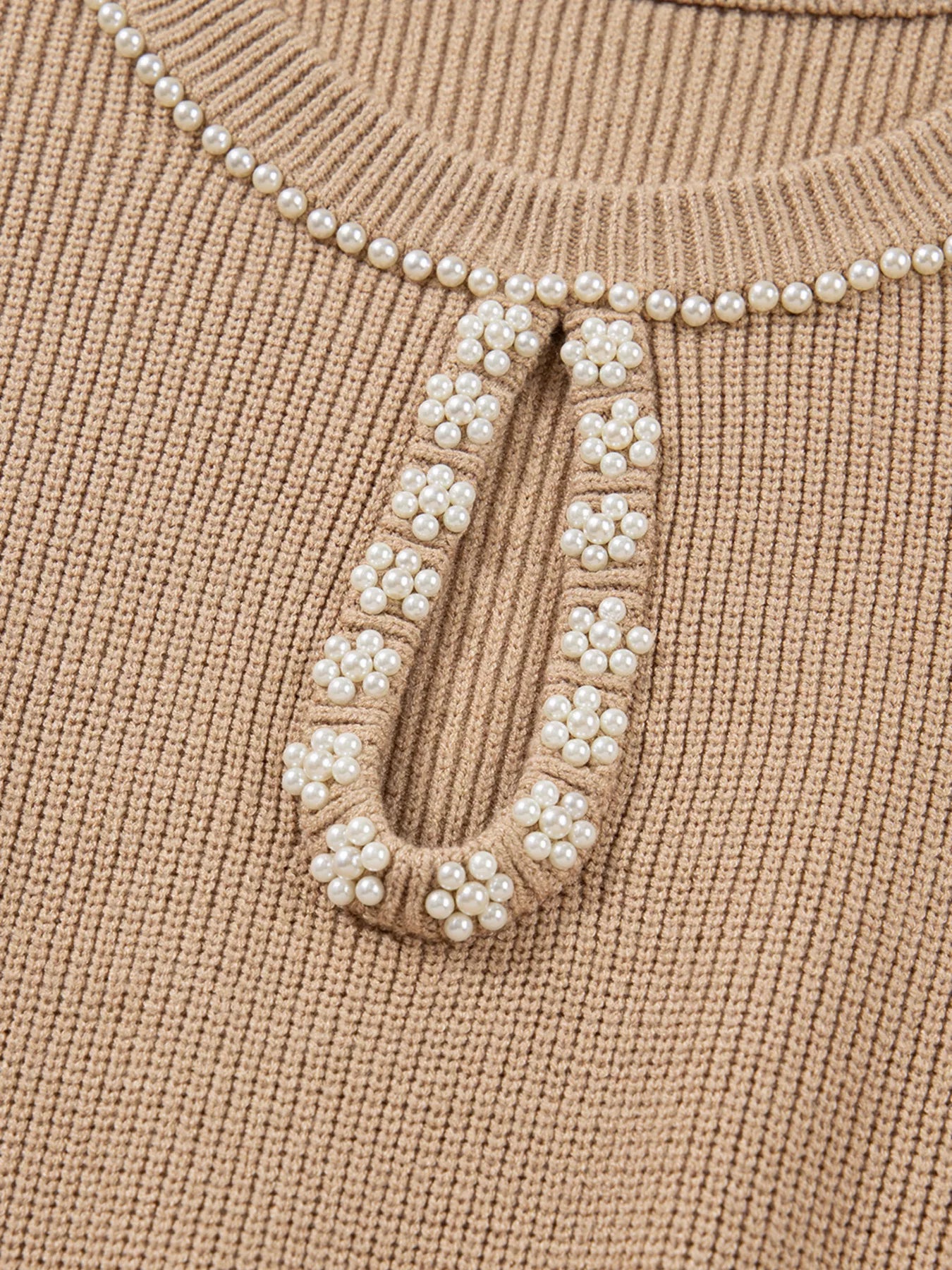 Close-up of stylish knit sweater dress for women featuring elegant pearl detailing and structured knit finish.