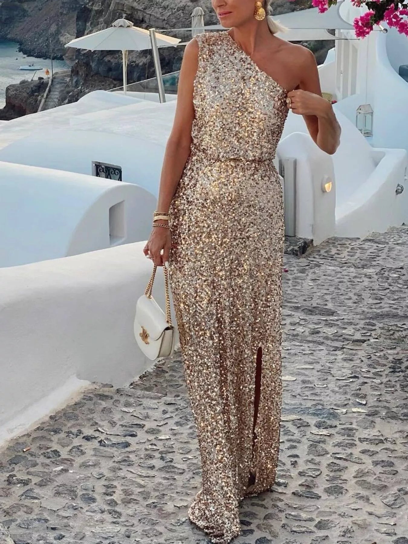 Sequin One-Shoulder Maxi Dress worn by a woman walking on a cobblestone path, showcasing its elegant and glamorous design.
